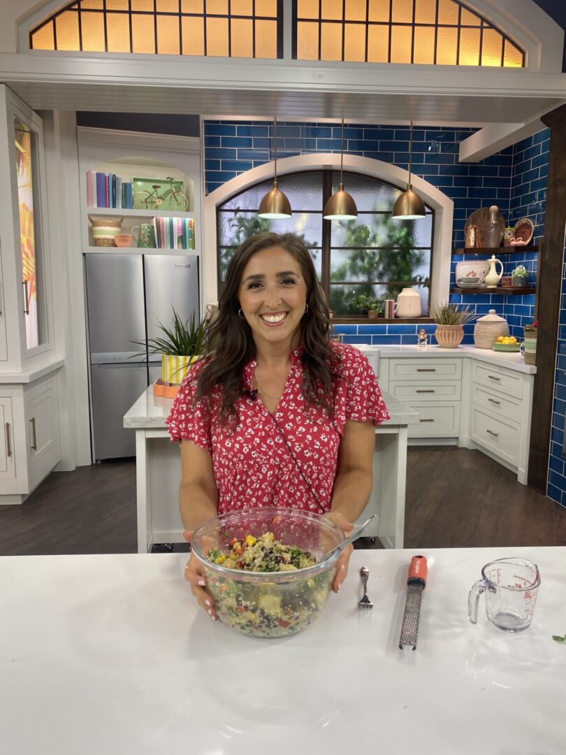 Smiling woman in kitchen studio holding salad bowl